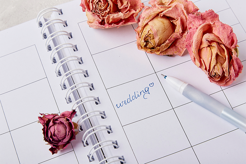 white planner with wedding written on one date, displayed open with florals on the edges of the planner