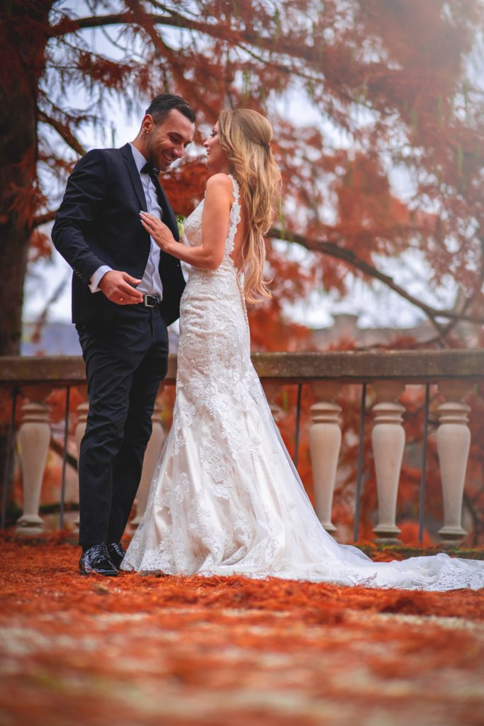 An Arizona bride and groom interact happily amidst red trees and fallen leaves