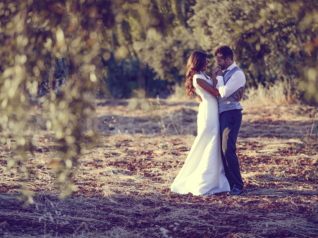 A groom kisses his bride’s hand in a clearing in the Arizona woods after their wedding