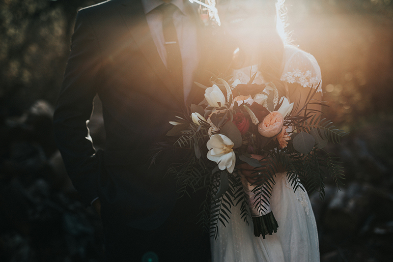 Wedding couple standing together holding a bouquet of flowers.