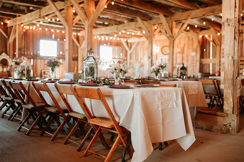 Budget friendly Arizona wedding venue in a rustic barn setting, string lights, cream colored linens and wood chairs