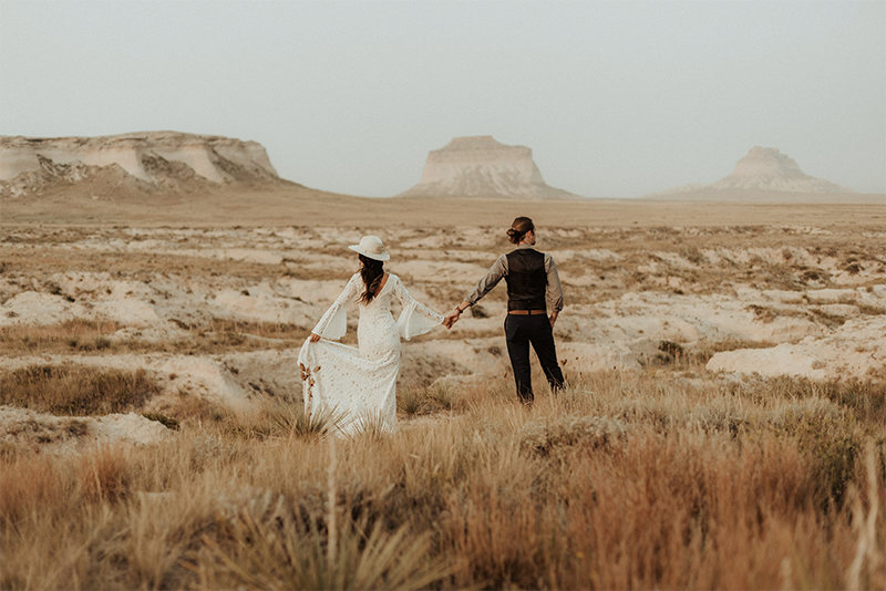 Arizona landscape with bride and groom holding hands searching for their perfect wedding venue in the desert
